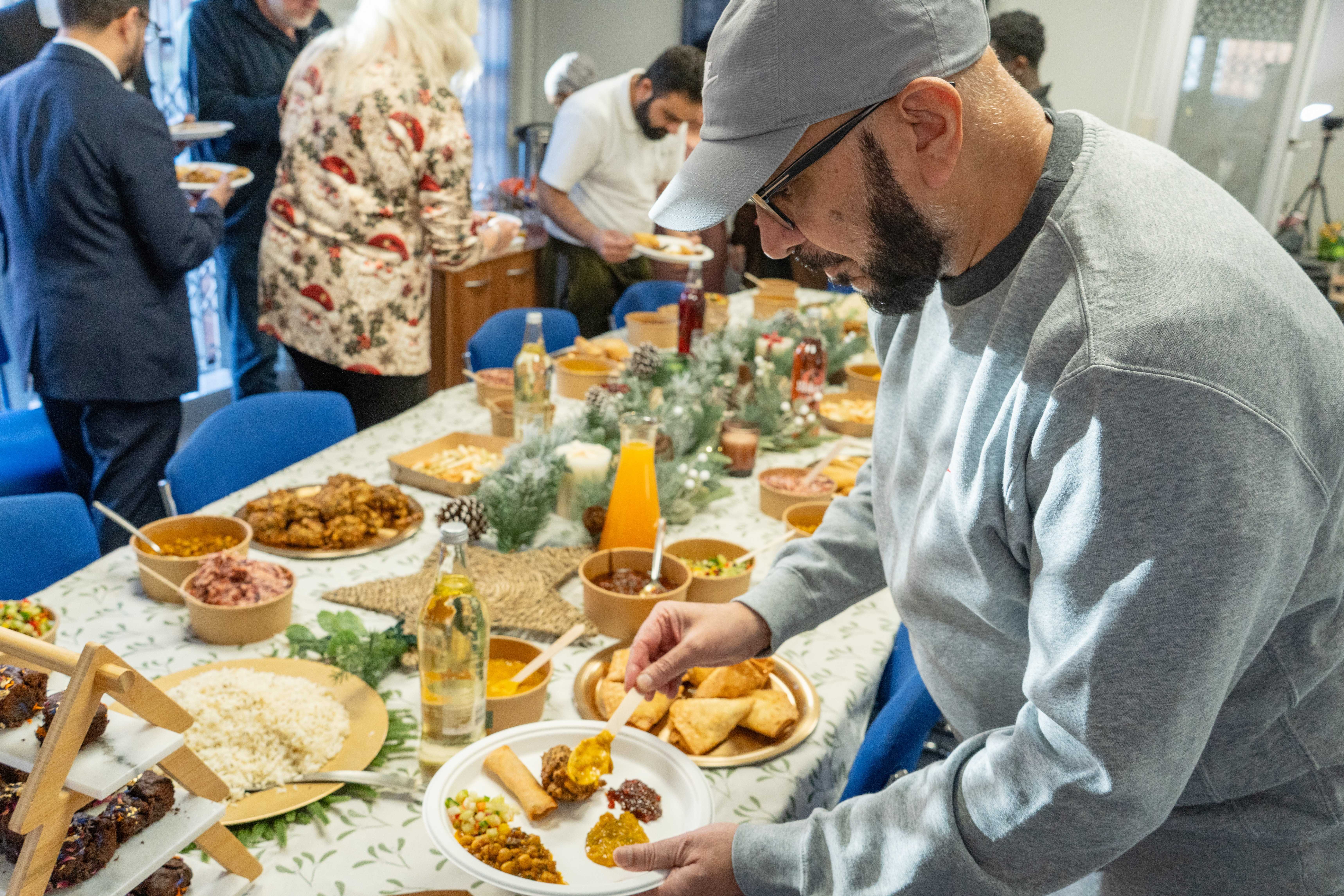 Guest preparing plate with curry and samosas